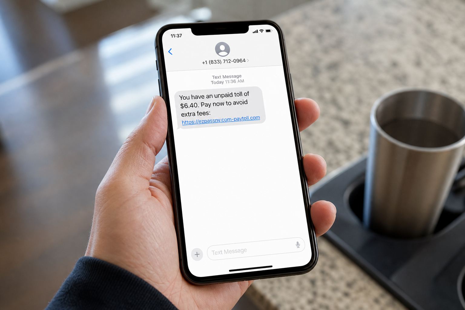 A hand holding a phone that shows a text about an unpaid toll.