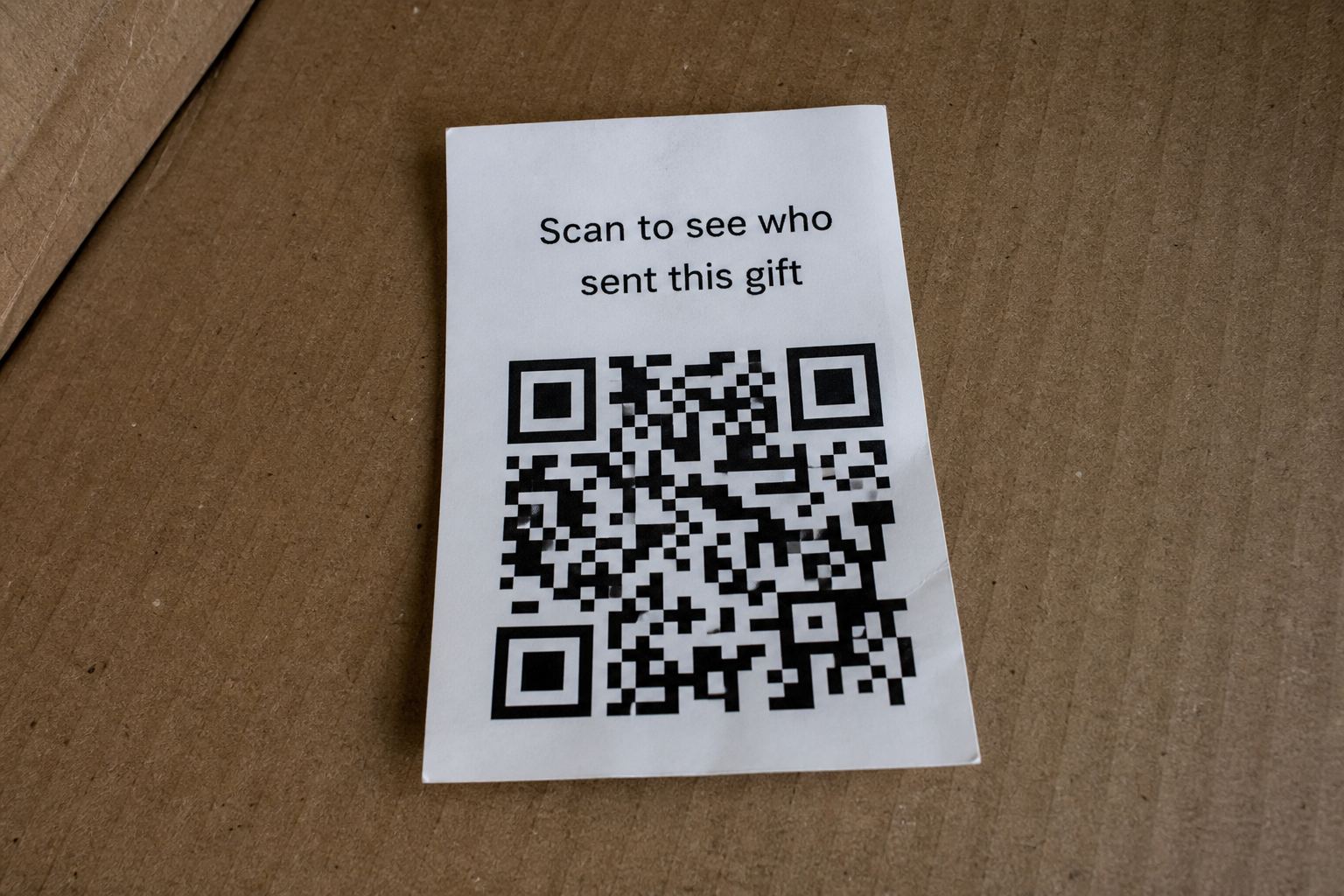 A printed card that says scan to see who sent this gift, with a real QR code.